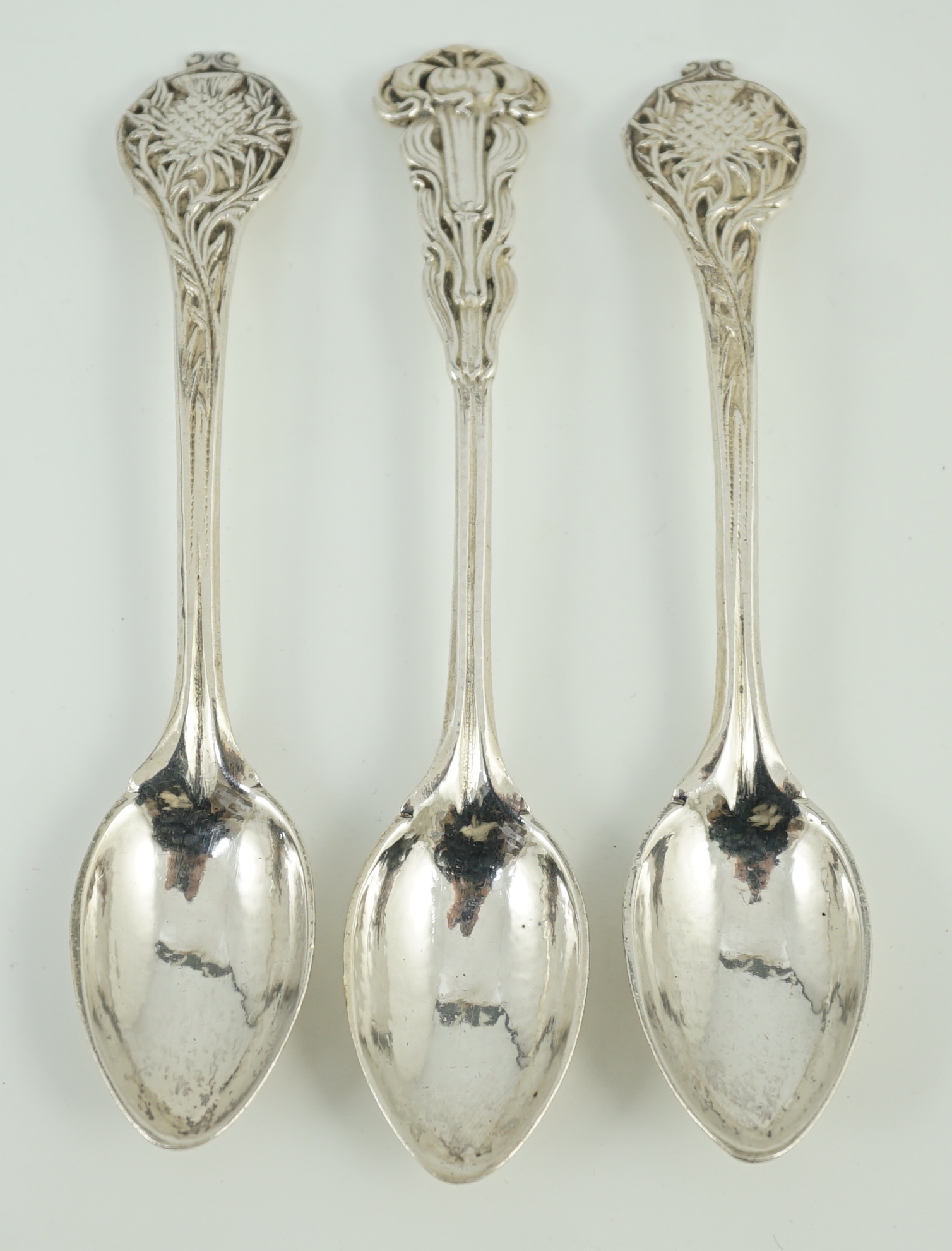 A cased set of three George V Arts & Crafts planished silver spoons by Omar Ramsden